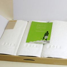 an open box with two folded towels on top of it and a green book in the middle