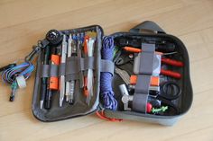 an open case filled with lots of different items on top of a wooden floor next to a pair of scissors