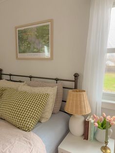 a bedroom with a bed, nightstand and window in the corner that has a painting on the wall