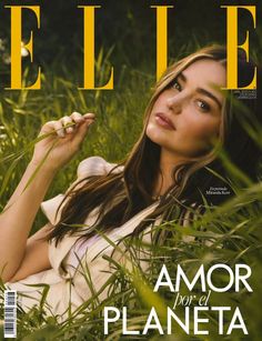 a woman laying in the grass on top of a magazine cover with her hand up to her face