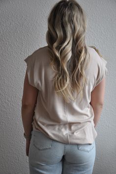 a woman with long blonde hair standing in front of a wall wearing jeans and a t - shirt