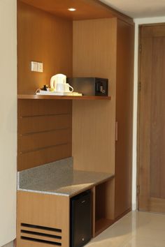 a microwave and coffee pot on top of a counter in a room with wood paneling