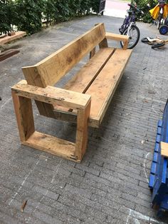 a wooden bench sitting on top of a brick road next to a blue trash can