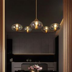 a dining room table and chairs in front of a mirror with lights hanging above it