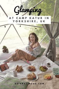 a woman sitting on top of a bed with food in front of her and the words glamping at camp katur in yorkshire, uk