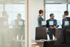 three men are talking in an office setting