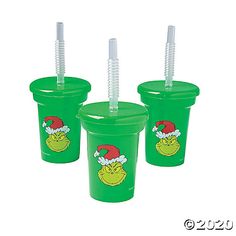 three plastic cups with straws in the shape of santa hats and grin face on them