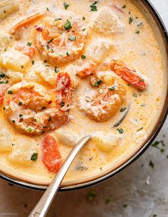 a close up of a bowl of soup with shrimp and grits in it on a white surface