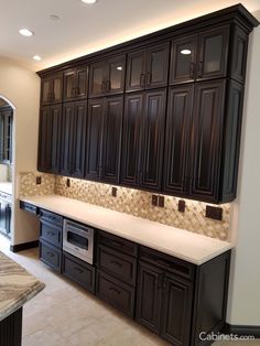 a large kitchen with black cabinets and white counter tops is pictured in this image from the front