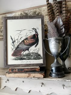 a bird sitting on top of a mantle next to a trophy and some feathers in a vase