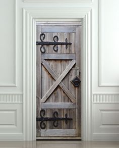 an old wooden door with wrought iron bars on the top and bottom, in front of a white wall