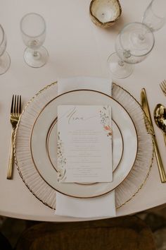 the table is set with gold and white plates, silverware, and napkins