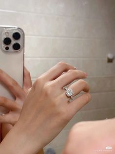 a woman's hand holding an iphone with a diamond ring on it