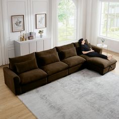 a woman laying on top of a brown couch in a living room