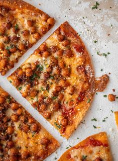 four slices of pizza with various toppings sitting on top of a white surface next to an orange slice