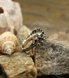 a silver ring sitting on top of a rock next to shells