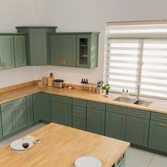 a kitchen with green cabinets and wooden counter tops