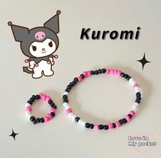 two bracelets with black and pink beads are on a white table next to a sticker that says kuromi