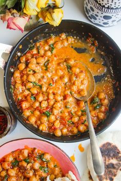 a pan filled with chickpeas and sauce on top of a table