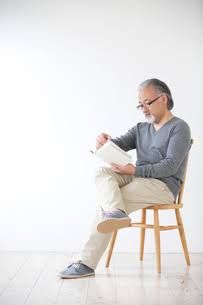 an older man sitting in a chair reading a book