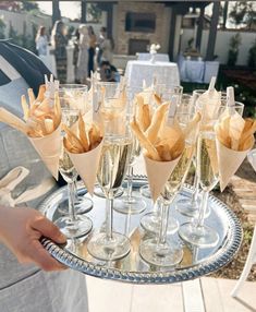 a silver tray topped with lots of glasses filled with champagne and fries on top of it