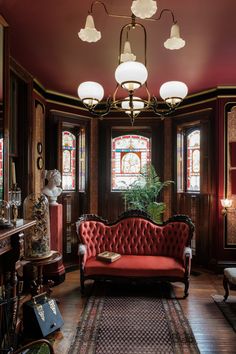 an ornate living room with red couches and stained glass windows in the wall behind them