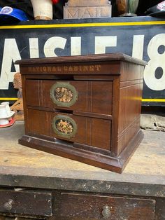 an old wooden chest with two drawers on it's sides, in front of a sign