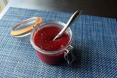 a glass jar filled with red liquid sitting on top of a blue place mat next to a spoon