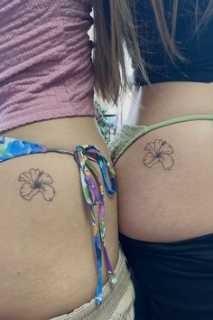 two women with tattoos on their butts and one has a flower tattoo on her lower back