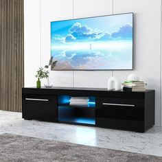 a flat screen tv mounted on the wall above a black entertainment center with blue lights