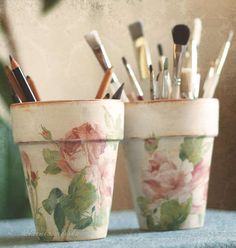 two flowered cups with makeup brushes in them