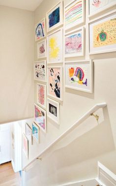 there are many framed pictures on the wall next to the banister and stair case