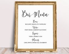 a sign that says bar menu in black and gold frame on a wooden table next to a white wall