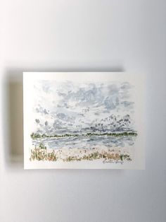 a watercolor painting of a beach with clouds in the sky and grass on the ground