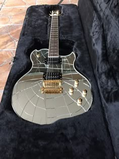 an electric guitar sitting on top of a black velvet case with gold trimmings