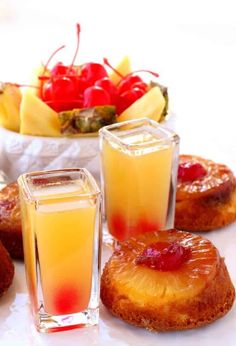 some pineapple upside down cakes with fruit in the bowl and on the plate next to them