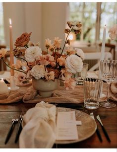 the table is set with candles and flowers in vases, napkins, and silverware