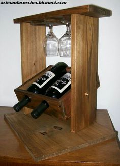 two wine glasses are sitting in an open wooden box on top of a table next to some bottles