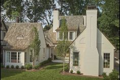 a white house with brown shingles and trees in the background