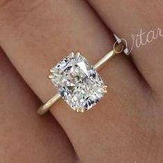 a close up of a person's hand with a diamond ring on their finger