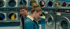 two people are standing in front of washing machines and looking at each other's faces