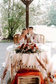 a bride and groom sitting at a table in front of a cross with the words free jarman's written on it