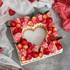 a heart shaped cake with strawberries and flowers on the top is surrounded by other decorations