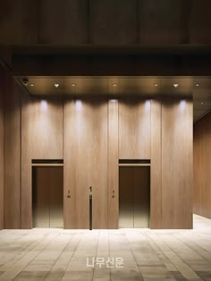 an empty room with three doors and two lights on the ceiling, in front of wooden paneled walls