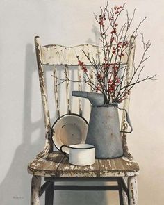 an old chair with a bucket and bowl on it, next to a vase filled with red berries