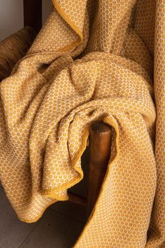 a yellow and white blanket sitting on top of a wooden chair