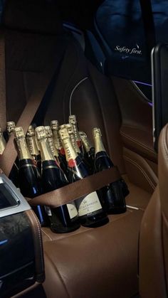 a bunch of bottles of champagne in the back seat of a car with brown leather seats