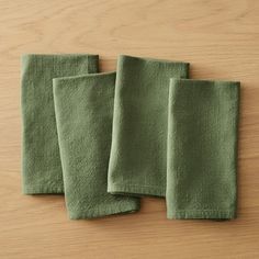 three green napkins sitting on top of a wooden table