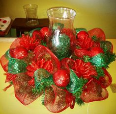 a glass vase sitting on top of a table filled with red and green christmas decorations