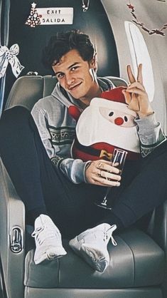 a man sitting on an airplane holding a stuffed animal and giving the peace sign with his hand